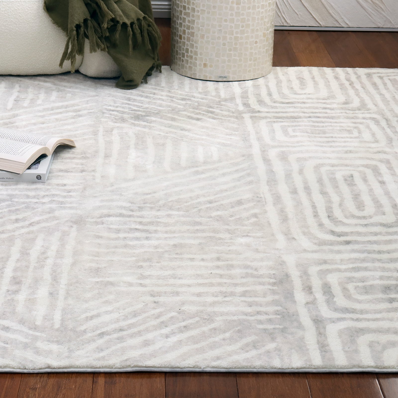 Duved 200x300cm Large Contemporary Indoor Floor Rug with subtle geometric patterns in off-white and pale gray, displayed on dark hardwood floor, enhancing a cozy living-room setting with a cream sofa and side table.