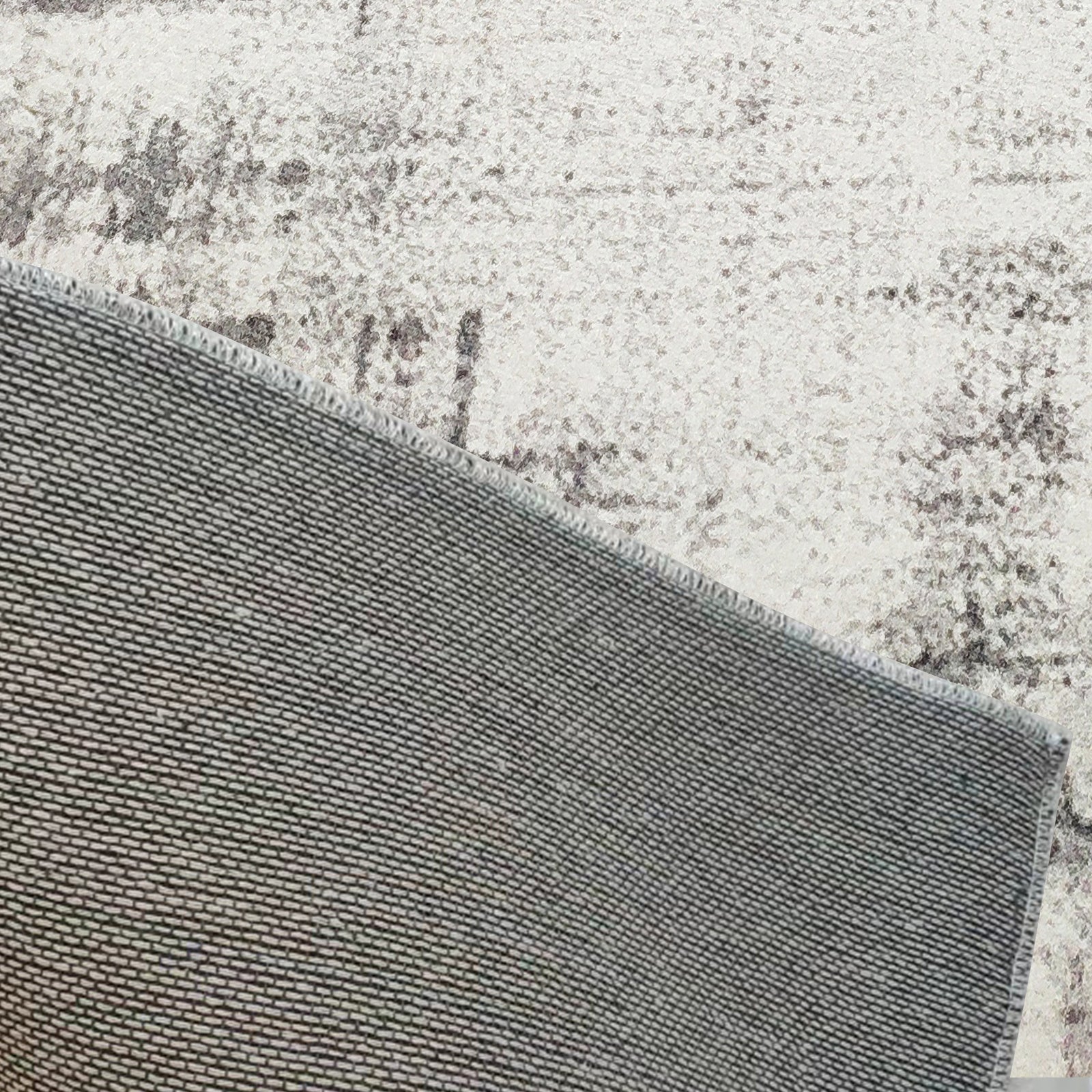 Franco 200x300cm Large Tufted Contemporary Indoor Rug, showcasing its backside, sits atop a larger mottled grey/cream carpet, highlighting its tightly woven texture and substantial size.