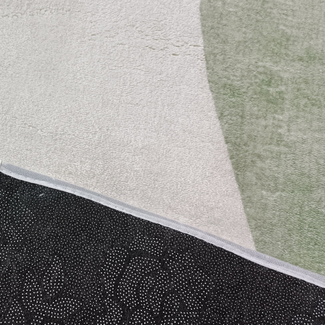 Gonas 200x300cm Large Abstract Indoor Floor Rug featuring a light beige background with a muted green shape, and a black, dot-patterned non-slip backing corner flipped over.