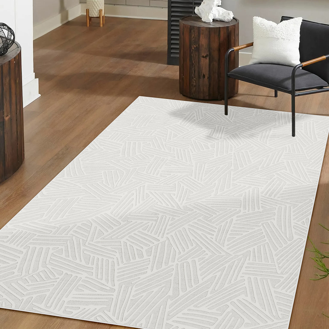 Malung 200x300cm Contemporary Indoor Floor Rug with a random stick-like line pattern, centered on a warm wood floor, complements a black lounge chair and dark-stained side table with sculpture.