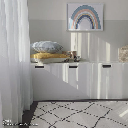 Melody Black and White Modern Floor Rug 200 x 300cm lies on the floor, featuring a subtle black-line diamond pattern on an ivory backdrop, complementing the minimalist playroom's decor.