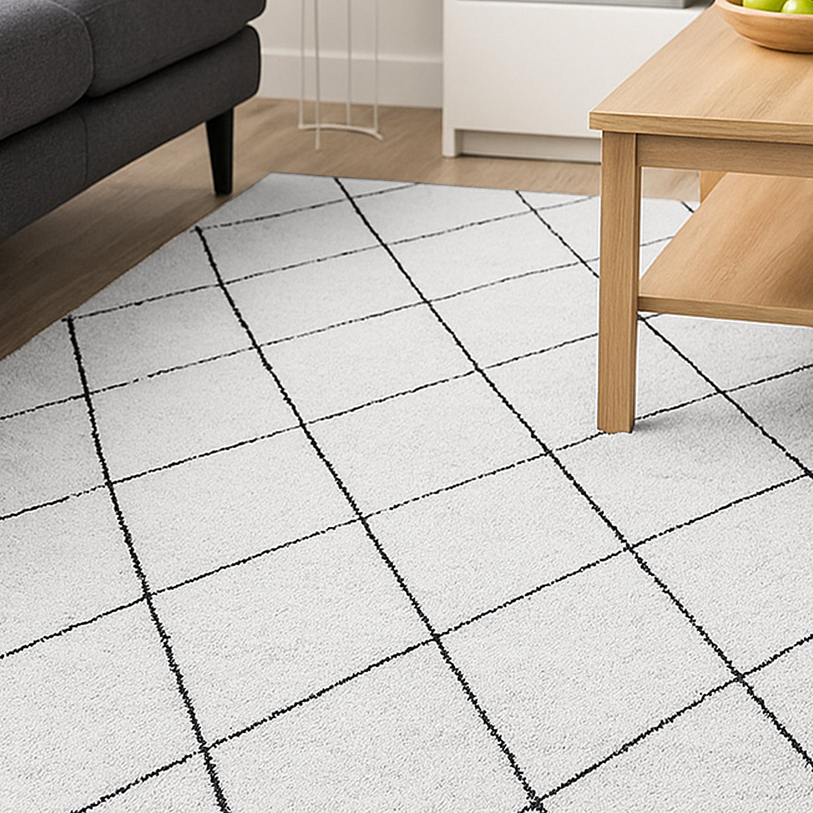 Milani 120x170cm Contemporary Printed Indoor Floor Rug features a light, almost white surface with black grid lines, set on a light wood floor, alongside a coffee table and dark-gray sofa.