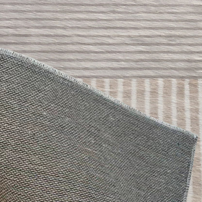 Corner view of Olivia 200x300cm Polyester Tufted Modern Abstract Indoor Rug, showcasing tightly-woven grey fabric with overlocked stitching on a light wood surface.