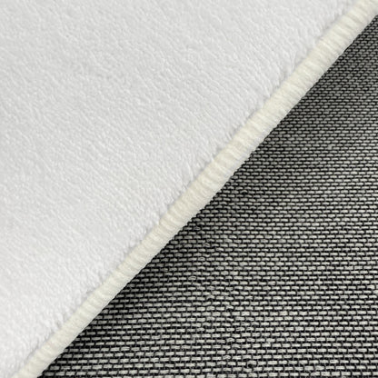 Close-up of Pavla 200 x 300cm Oval Shaggy Rug in Cream White, showcasing its plush, soft texture on top, contrasted with a coarser, grey-and-black woven textile beneath, highlighting its luxurious comfort.