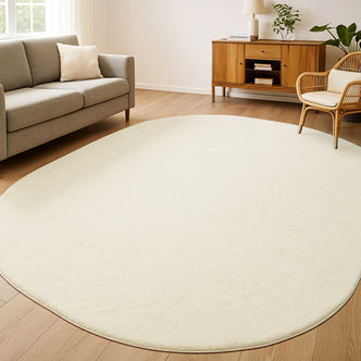 Pavla 240 x 330cm Oval Soft Rug in Beige, softly textured, sits on light hardwood floors, enhancing a minimalist living room with its plush, wool-like pile and soothing neutral tone.