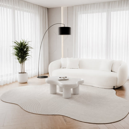 Penina 300 x 400cm Cloud Soft Rug in Neutral in a light-filled room, with a sculptural coffee table, curvy sofa, and tall plant, enhancing the airy, minimalist ambiance.