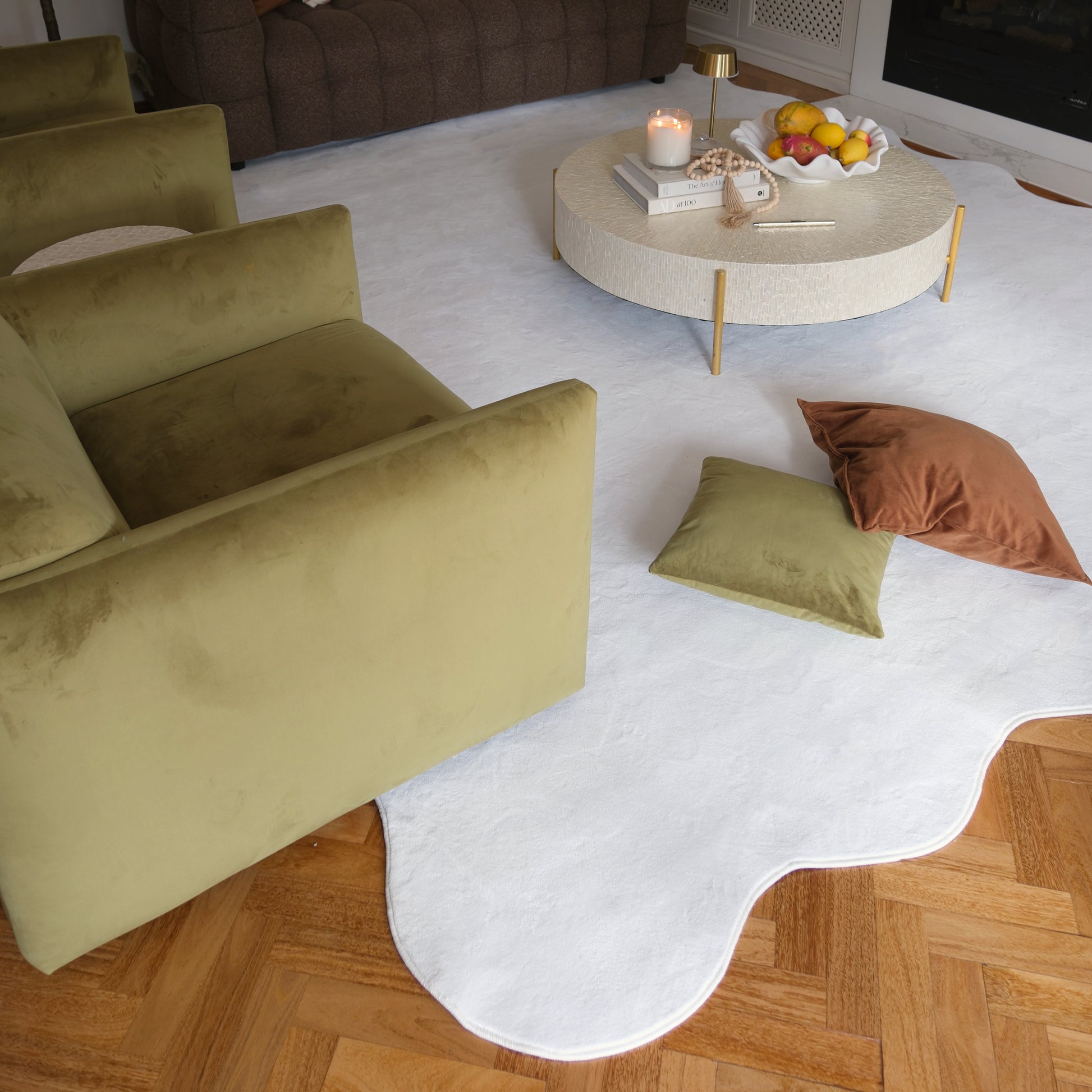The Pixie 240x330cm Large Wavy Soft Rug in Cream White features a plush, wavy design resembling a cloud, set in a cozy living room with velvet furniture and a round coffee table.