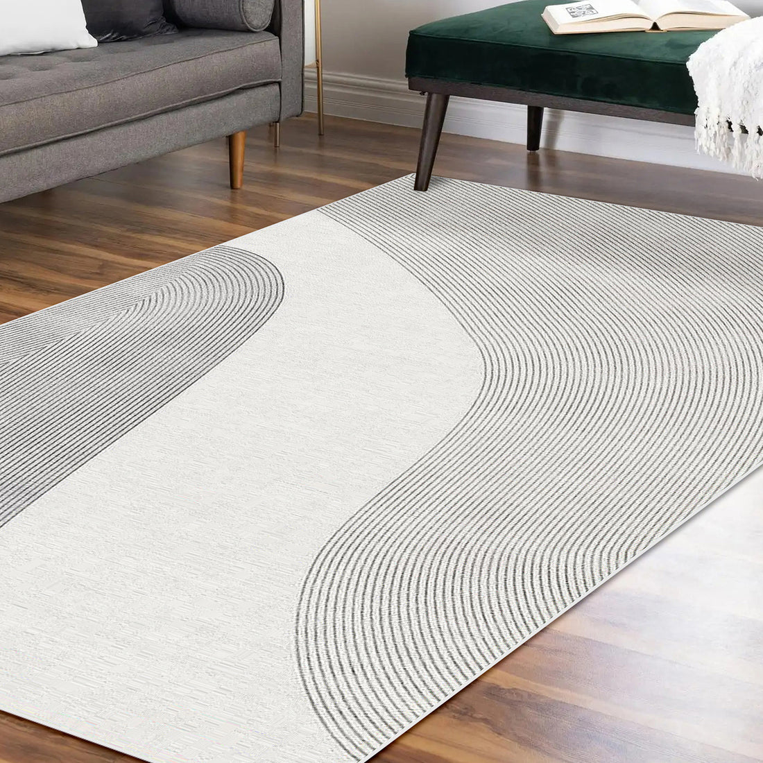 Ramvik 200x300cm Abstract Indoor Floor Rug with gray wave-like lines on an off-white background, complementing a minimalist lounge with a mid-century sofa and green velvet bench.