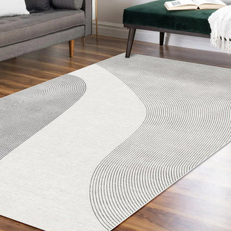 Ramvik 200x300cm Abstract Indoor Floor Rug with gray wave-like lines on an off-white background, complementing a minimalist lounge with a mid-century sofa and green velvet bench.