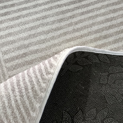 Rosson 200x300cm Large Modern Abstract Indoor Rug with a cream-colored textured, striped pile, corner flipped revealing black non-slip backing, placed on a light carpet.