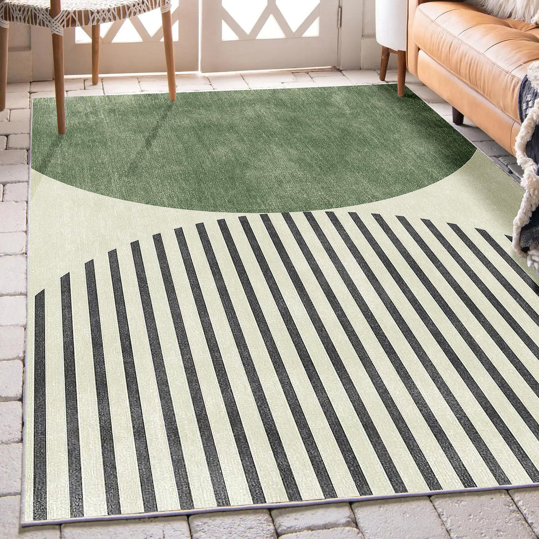 Vannebo Modern Abstract Floor Rug 200 x 300cm displayed on a light tile floor, featuring a green semicircle and black stripes. Shown with a tan leather sofa and wooden side chair.