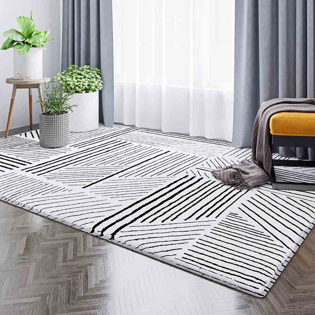 Vikki 200x300cm Large Abstract Contemporary Floor Rug with black geometric patterns on white, enhancing a modern room with wood flooring, sheer curtains, potted plants, and a mustard-yellow bench.