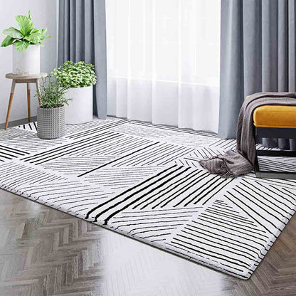 Vikki 200x300cm Large Abstract Contemporary Floor Rug with black geometric patterns on white, enhancing a modern room with wood flooring, sheer curtains, potted plants, and a mustard-yellow bench.