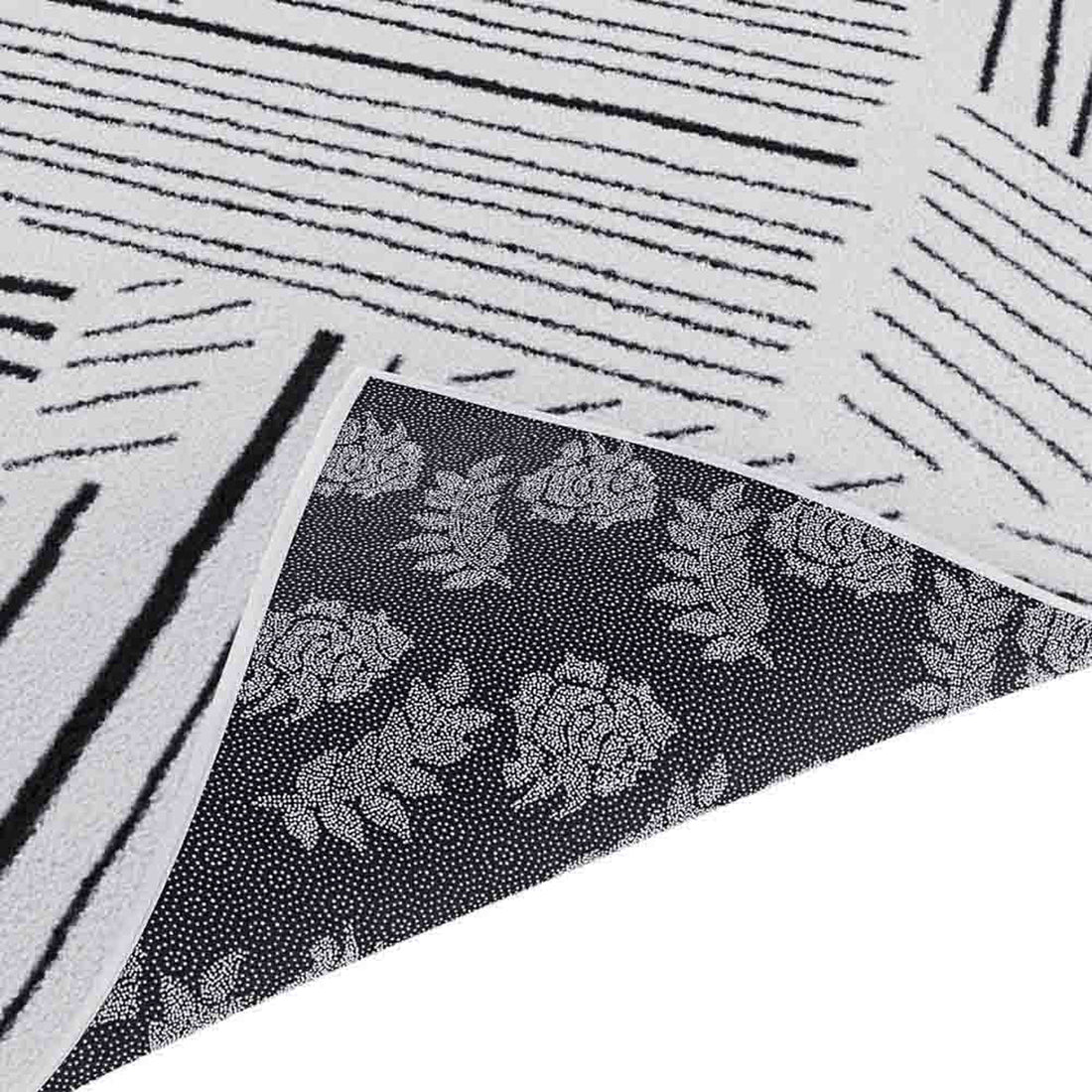 Vikki 200x300cm Large Abstract Contemporary Floor Rug shown with reversible sides; one side features irregular black stripes on off-white, the other displays rose-and-leaf motifs on a dark background.