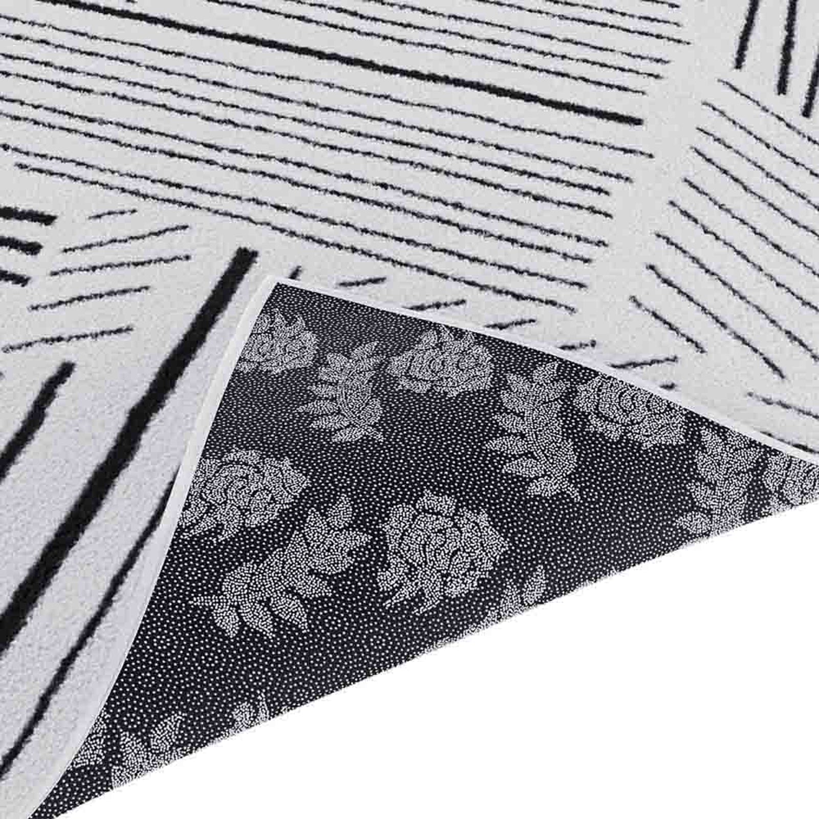 Vikki 200x300cm Large Abstract Contemporary Floor Rug shown with reversible sides; one side features irregular black stripes on off-white, the other displays rose-and-leaf motifs on a dark background.