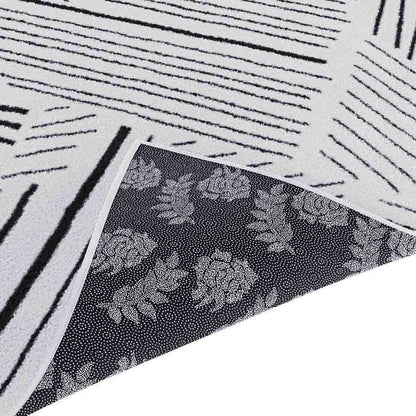 Vikki 200x300cm Large Abstract Contemporary Floor Rug shown with reversible sides; one side features irregular black stripes on off-white, the other displays rose-and-leaf motifs on a dark background.
