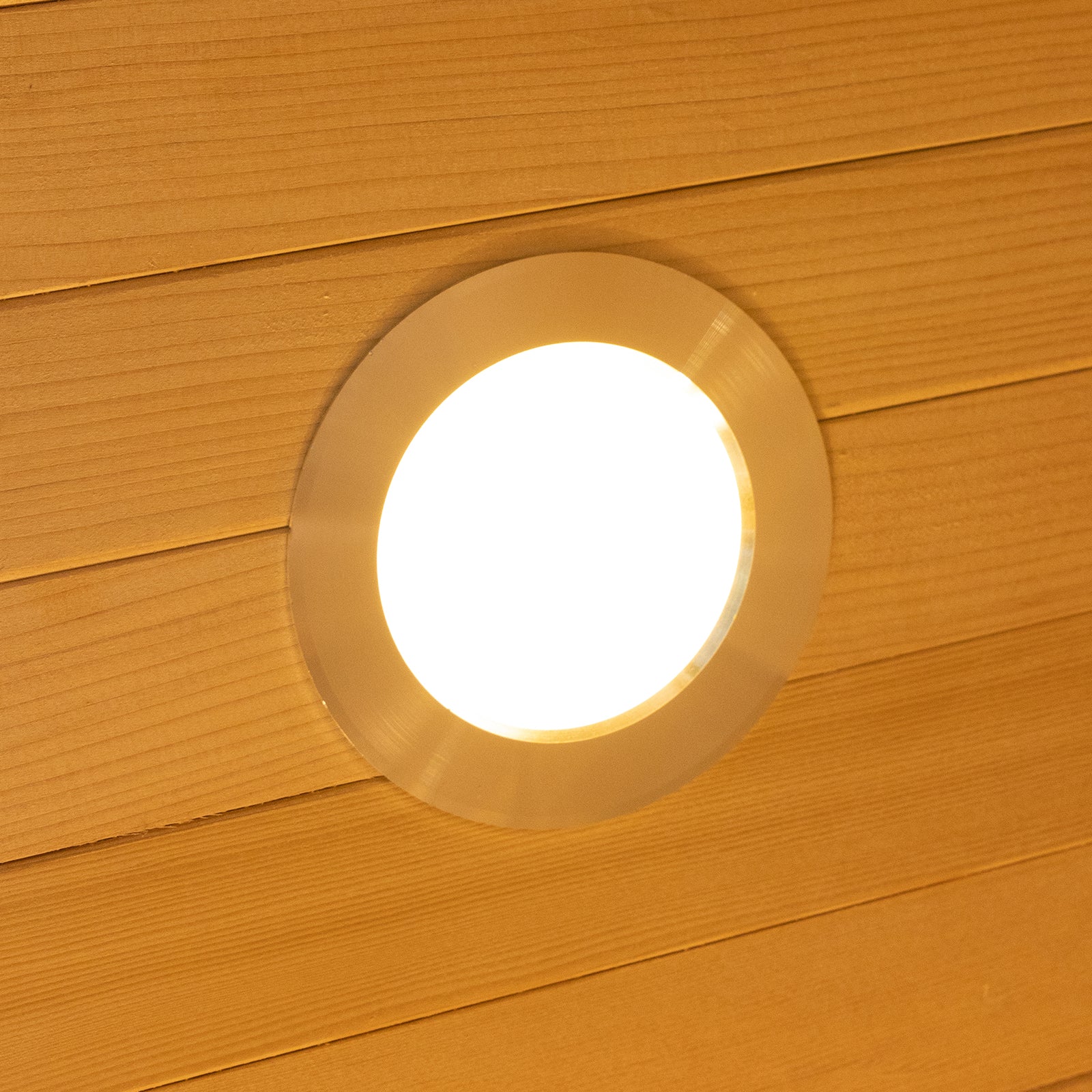 Harlow 2 Person Canadian Hemlock Infrared Home Sauna shown with a round recessed LED downlight in a wood-plank ceiling, creating a warm, inviting atmosphere for relaxation and wellness.