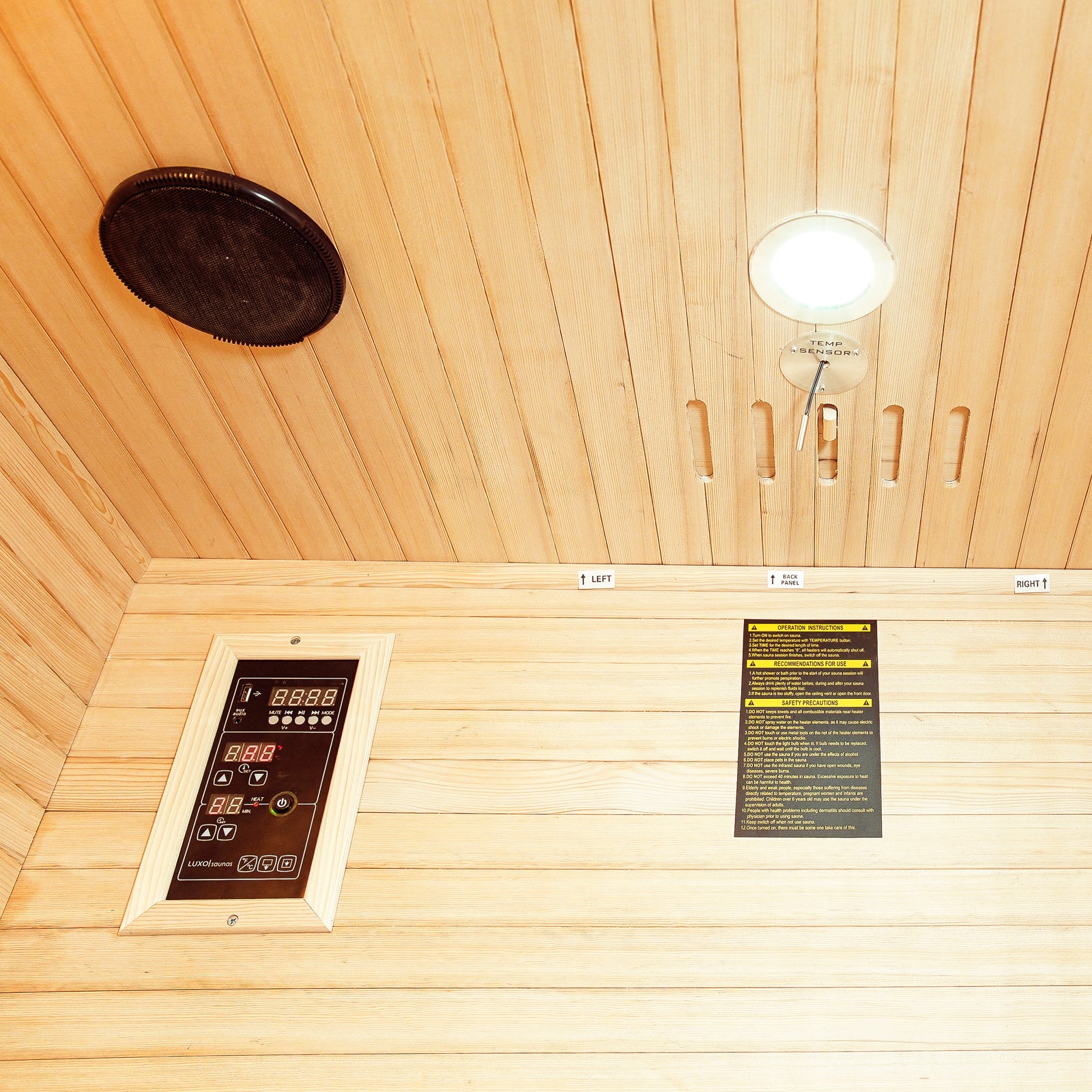 Taavi 2 Person Ceramic Infrared Indoor Home Sauna ceiling view showing a round speaker, recessed light with TEMP SENSOR, safety label, and LUXUSAUNA digital control panel with LED readouts and buttons.