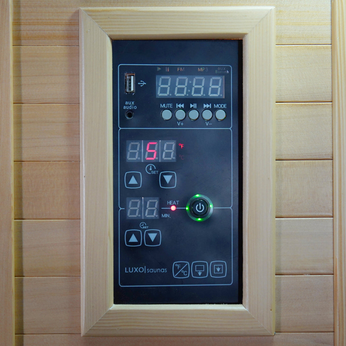 Taavi 4-Person Corner Carbon Fibre Infrared Indoor Sauna featuring a built-in digital control panel with audio/media interface, temperature settings, and timer display, set into a wooden wall for home relaxation.