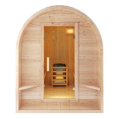 Tarni 2-Person Finnish Outdoor Sauna – Fir Wood: A barrel-shaped sauna with glass door revealing wooden benches and a LUXO Saunas heater with stones, embodying a private, traditional Finnish retreat.