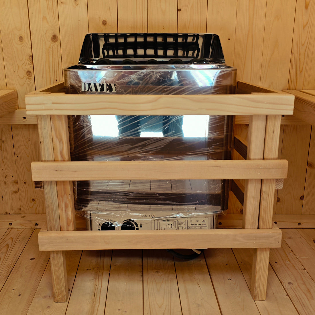 Tarni 2-Person Finnish Outdoor Sauna – Fir Wood features a Davey electric heater with a protective wooden guard, installed in a wood-paneled sauna cabin for backyard relaxation and wellness.
