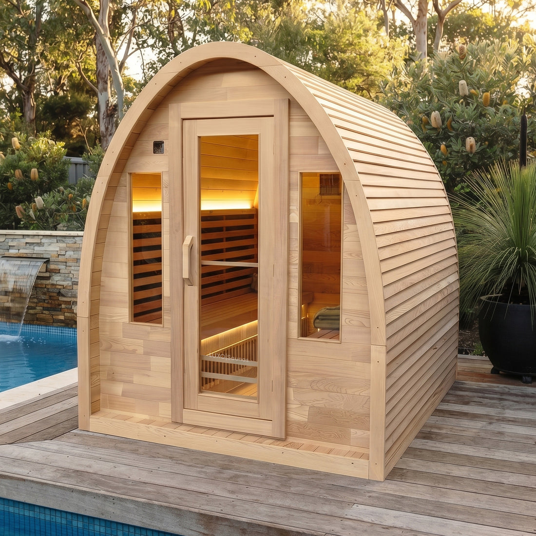 Wooden outdoor sauna on a deck beside a pool with greenery around it