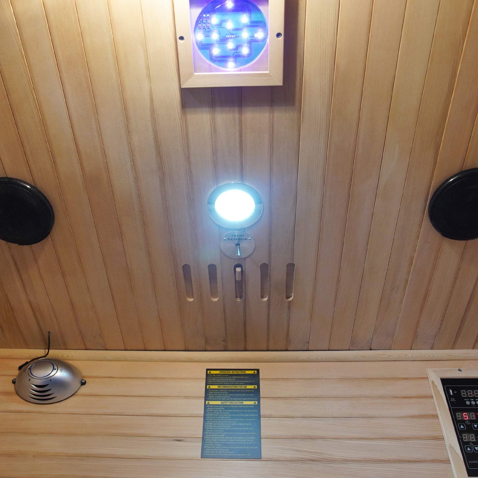 Valo 2-Person Canadian Hemlock Carbon Fibre Home Sauna Cabin featuring a sleek black control panel and wooden interior, illuminated by an LED light, offering a luxurious, energy-efficient sauna experience.