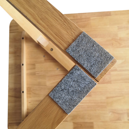 Close-up of Adelina 180cm Rectangular Hardwood Dining Table Natural, showcasing two uniquely-shaped wooden legs with grey felt pads on a light wood surface, highlighting its durable craftsmanship and stylish design.