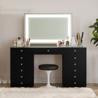 Adeline LED Mirror Storage Dressing Table in Black with glass top, LED-lit mirror, and 13 drawers. Features assorted cosmetics on top, a white stool, and a plush rug beneath.