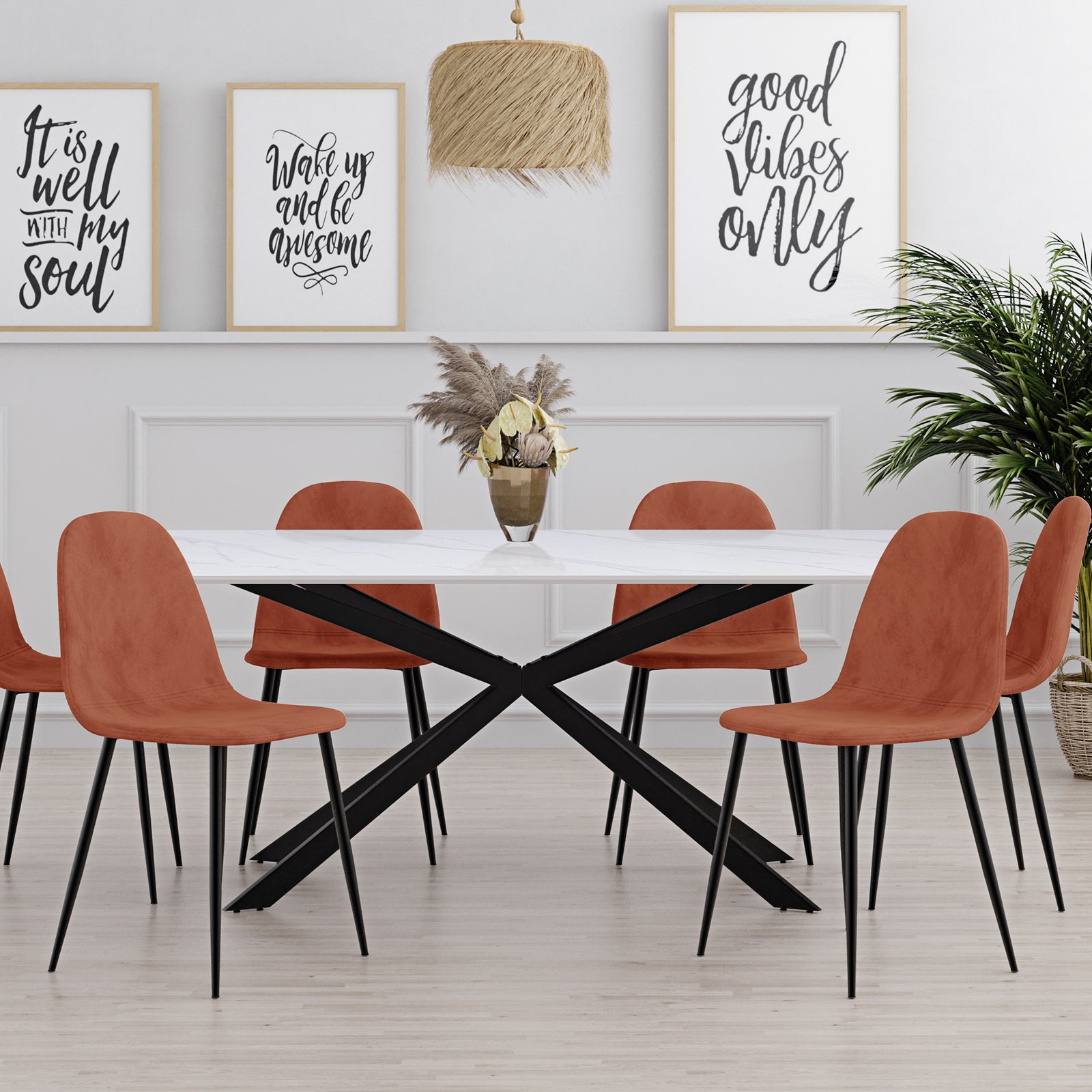 Alfred 180cm Modern Pedestal Dining Table features a sleek white-marble top and black metal “X”-style base, centered with a vase of dried pampas grasses, surrounded by six rust-orange chairs.