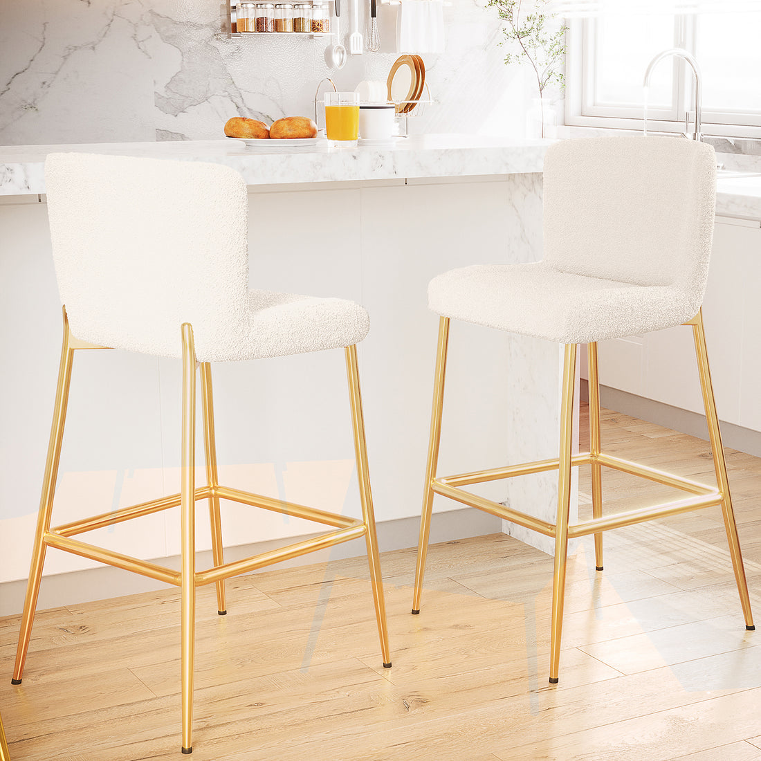 Bernie High Back Boucle Bar Stool Set of 2 in White, featuring plush off-white upholstered seats with gold-finished legs and a square footrest, accentuates a modern kitchen's marble and wood elements.