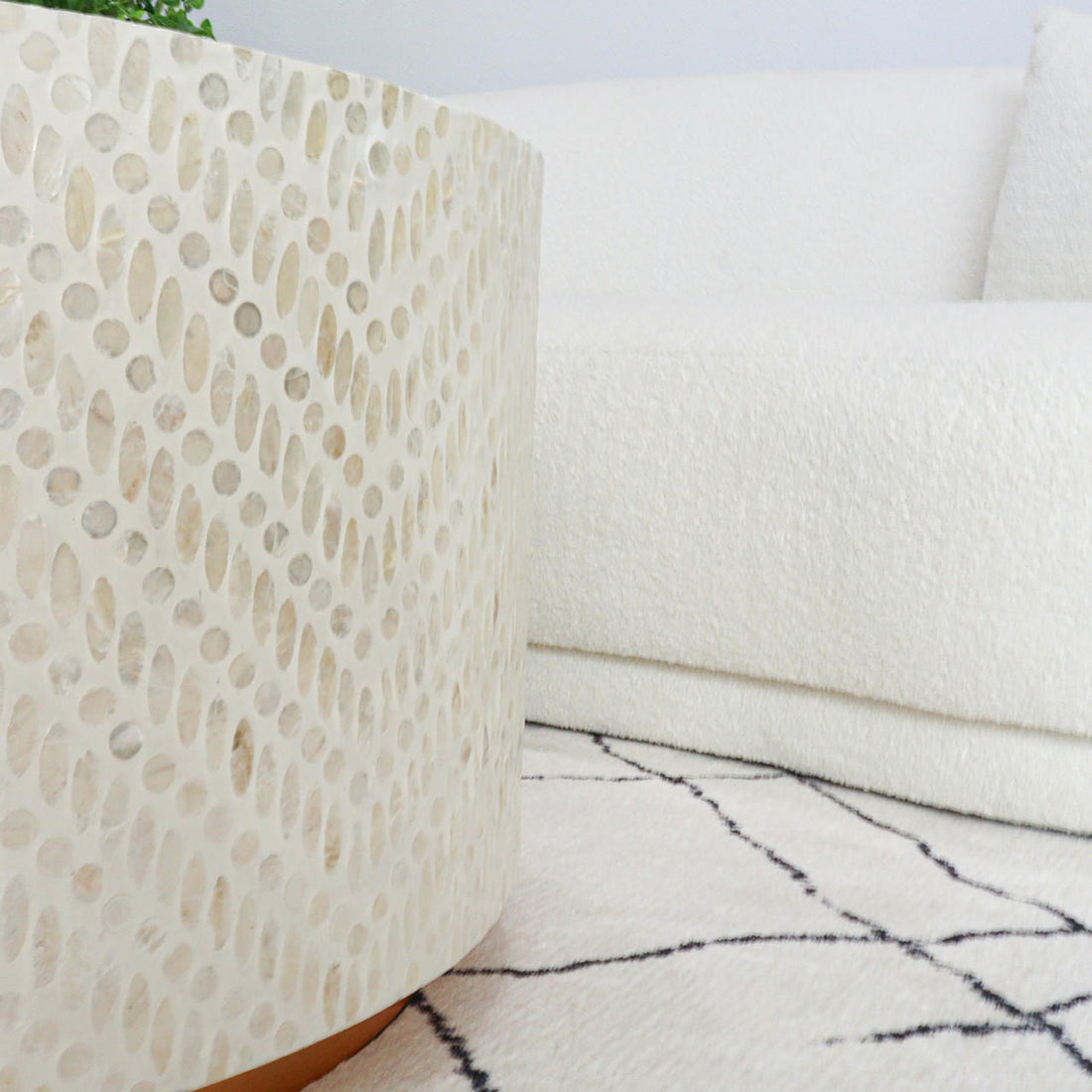 Bisera 91cm Mother of Pearl Inlay Coffee Table Sand, showcasing a detailed mother-of-pearl mosaic on its surface, next to a white couch and a round white object, enhancing its luxurious appeal.