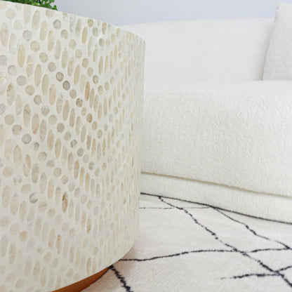 Bisera 91cm Mother of Pearl Inlay Coffee Table Sand, showcasing a detailed mother-of-pearl mosaic on its surface, next to a white couch and a round white object, enhancing its luxurious appeal.