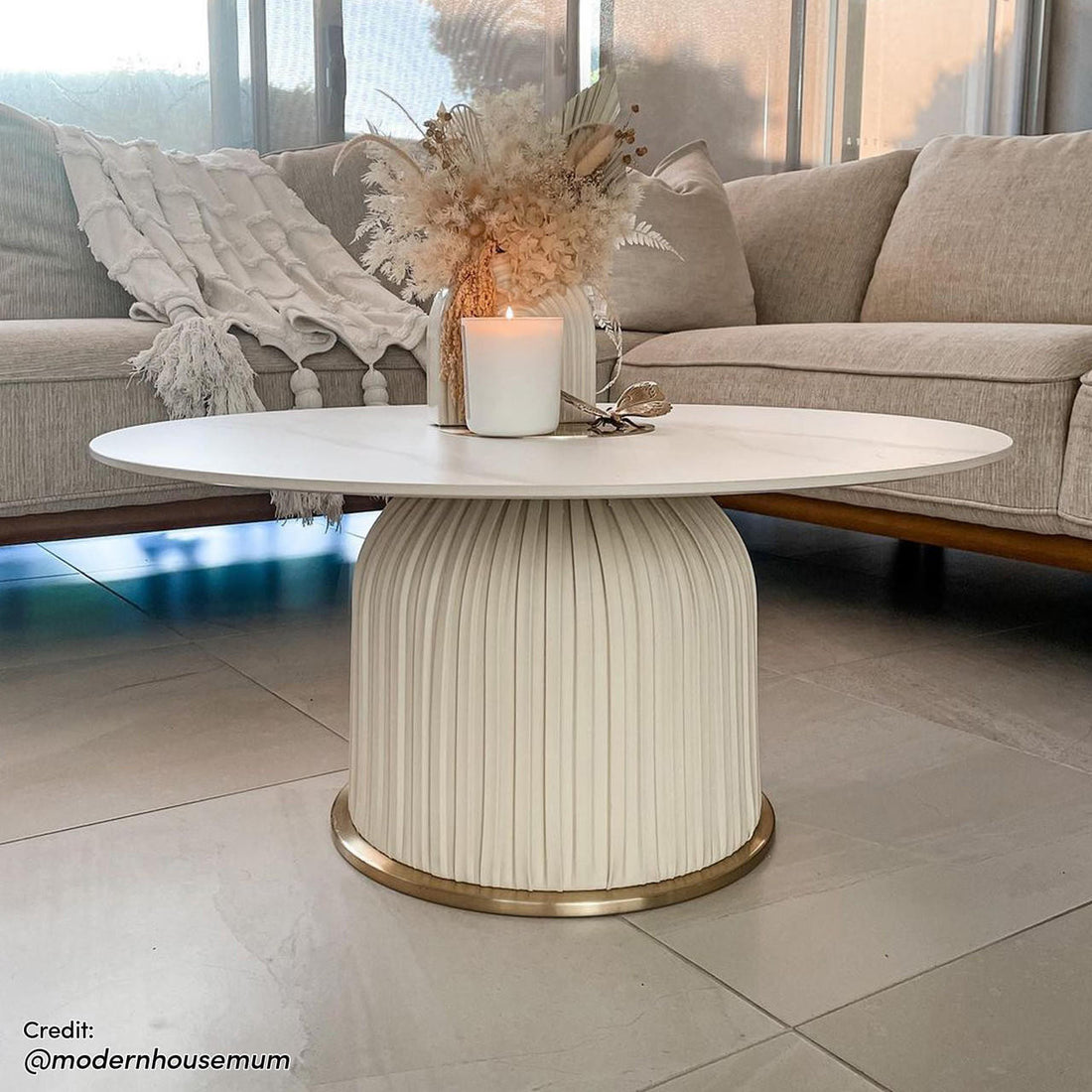 Combee 80cm Sintered Stone Coffee Table Cream White displayed indoors, showcasing its smooth stone top and unique design, accompanied by furniture elements like a couch and vase, highlighting its versatile placement.
