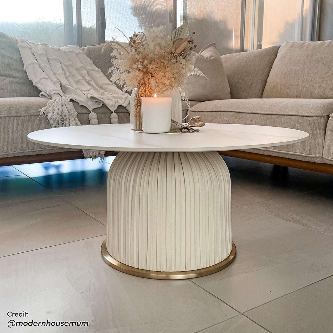 Combee 80cm Sintered Stone Coffee Table Cream White displayed indoors, showcasing its smooth stone top and unique design, accompanied by furniture elements like a couch and vase, highlighting its versatile placement.