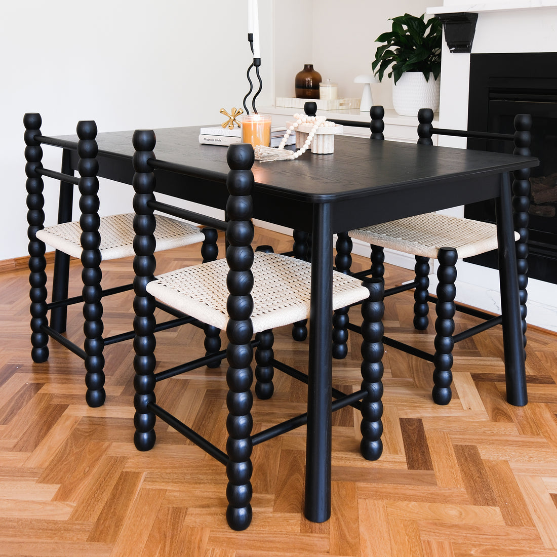 Close-up of the Em Solid Oak Dining Chair Set of 2 in Black, showcasing the classic bobbin-style frame and natural fibre woven seat, highlighting its elegant design and sturdy construction.