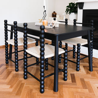 Close-up of the Em Solid Oak Dining Chair Set of 2 in Black, showcasing the classic bobbin-style frame and natural fibre woven seat, highlighting its elegant design and sturdy construction.