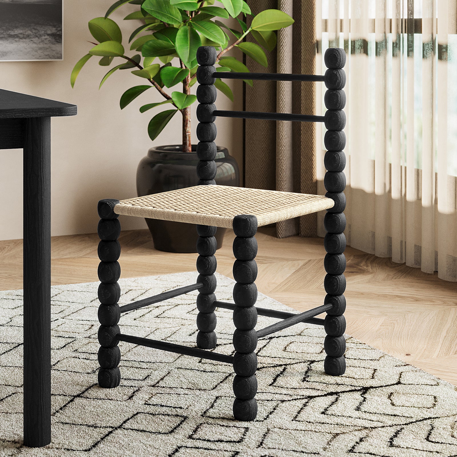 Em Solid Oak Dining Chair Set of 2 - Black, featuring a classic bobbin-style frame and natural fibre woven seats, displayed alongside a coffee table and houseplant, showcasing its elegant, durable design.