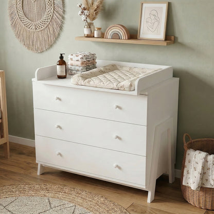 White dresser with three drawers and changing station styled in nursery room