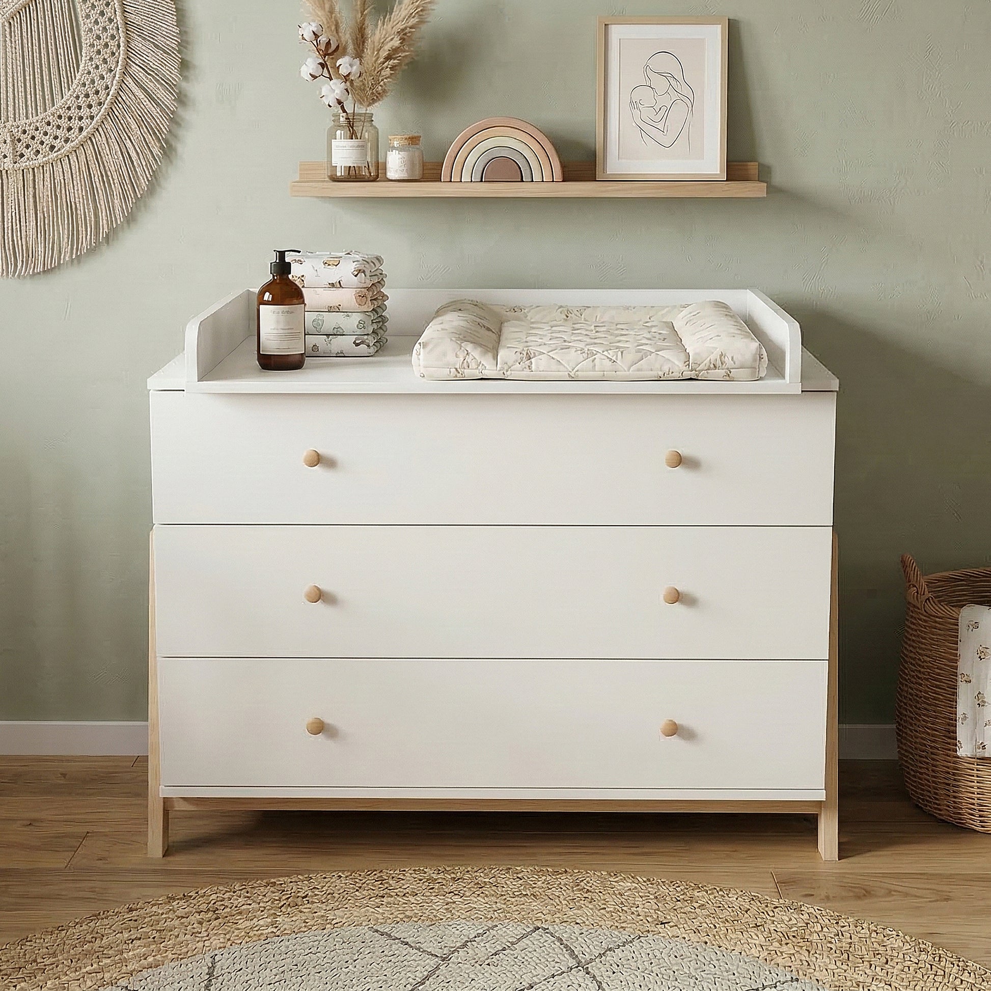 White dresser used as a changing table in a styled nursery with decor and changing pad