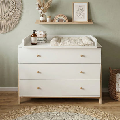 White dresser used as a changing table in a styled nursery with decor and changing pad