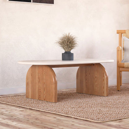 Kerry 120cm Solid Oak Oval Coffee Table - White Natural features a sleek oval design with a white tabletop, supported by sturdy natural oak legs, complemented by a houseplant and rug for a chic living room setup.