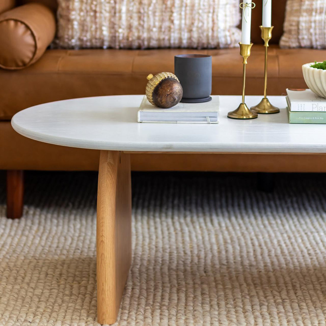 Close-up of the Kerry 120cm Solid Oak Oval Coffee Table - White Natural, showcasing its sturdy natural wood legs and sleek white oval tabletop, perfect for modern and contemporary living spaces.