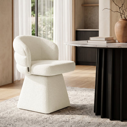 Cream bouclé swivel dining chair with a curved channeled back, chunky square pedestal base, and rounded seat.