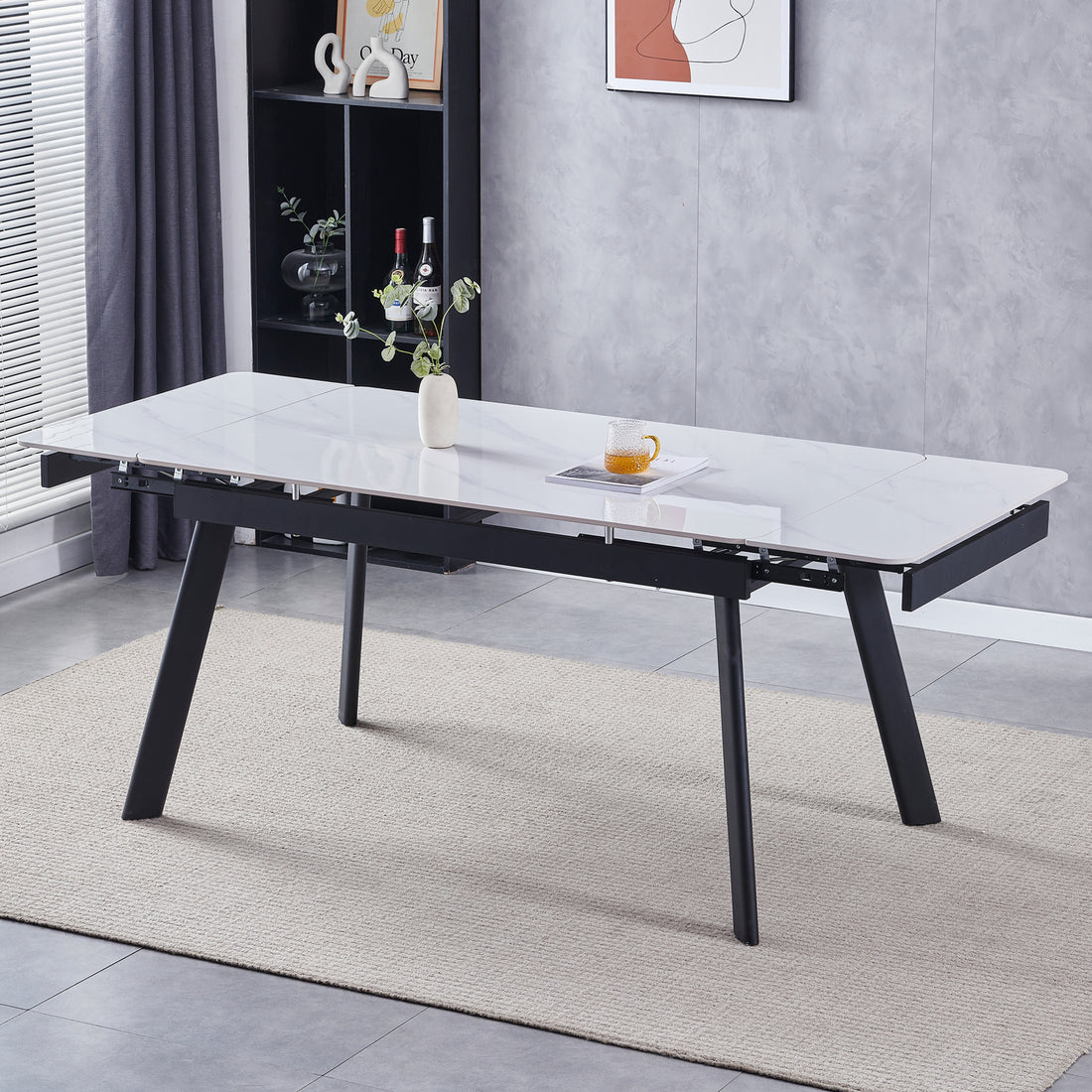 Rheed 197cm Extendable Ceramic Porcelain Dining Table White with glossy marble-effect top, black angled legs, styled with a ceramic vase, green sprigs, magazine, glass mug on beige rug.