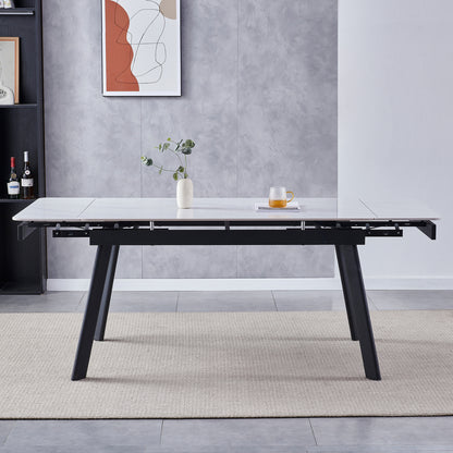 Rheed 197cm Extendable Ceramic Porcelain Dining Table White with a marble-effect top, black angled legs, and partially extended leaves, adorned with a ceramic vase and glass mug on a woven rug.
