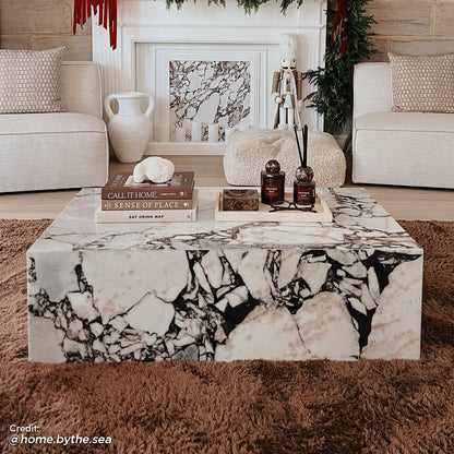 Solene 100cm Coffee Table in Real Blue Galaxy Marble features a white background with bold black veining, topped with books and decor, set in an elegant, cozy living room scene.