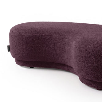 Kidney-bean shaped upholstered seating in rich plum color on a white background