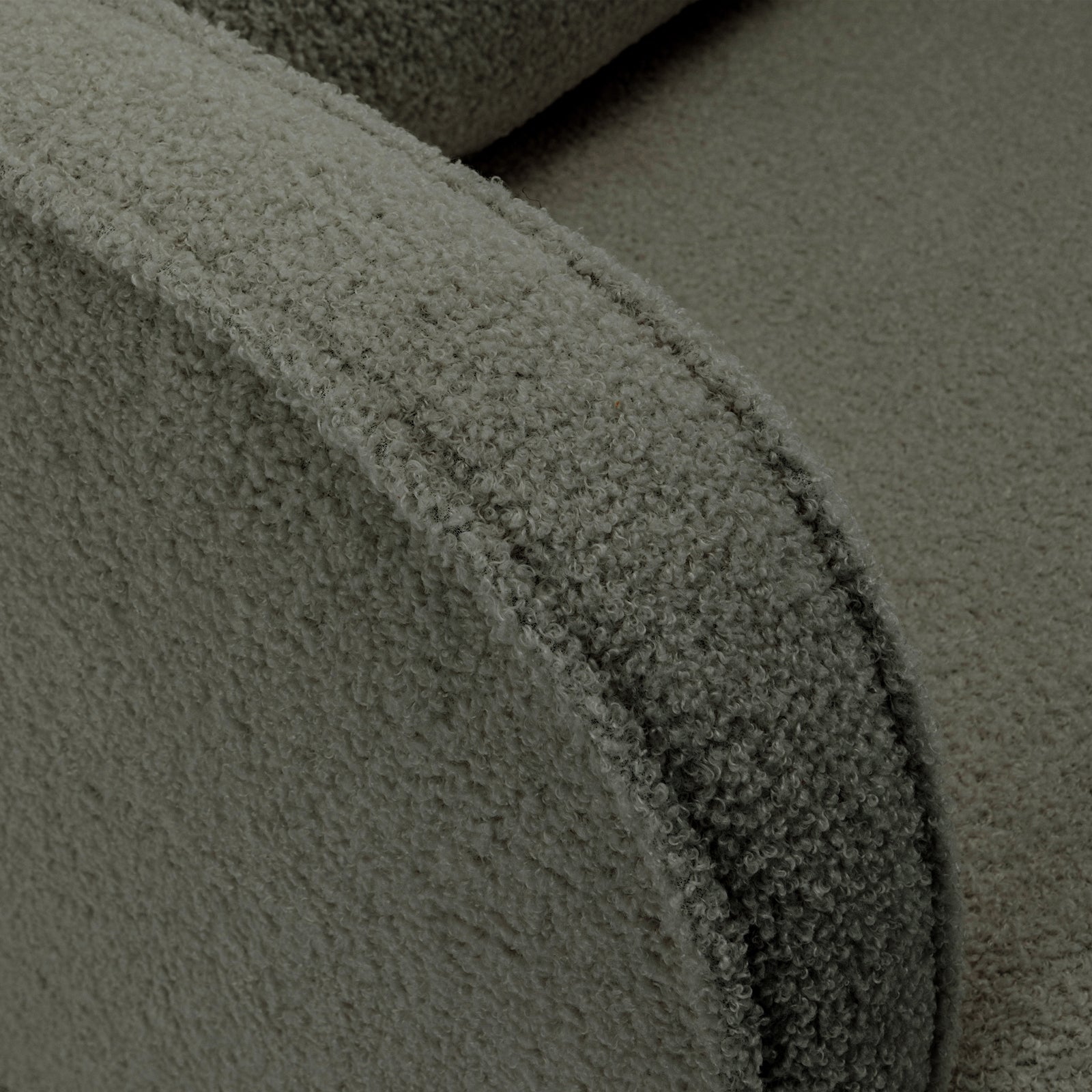 Close-up of Aura Bouclé Rocking Chair with Ottoman in Green, showcasing the textured bouclé fabric on the curved armrest and part of the seat, highlighting its soft and inviting design.