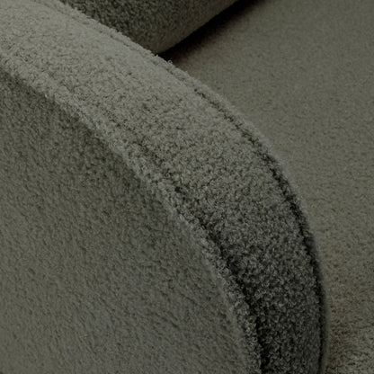 Close-up of Aura Bouclé Rocking Chair with Ottoman in Green, showcasing the textured bouclé fabric on the curved armrest and part of the seat, highlighting its soft and inviting design.